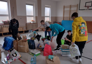 Uczniowie klasy VIII segregujący zebrane rzeczy dla uchodźców