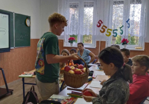 Uczeń klasy VIII częstujący jabłkami uczniów klasy V