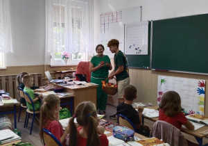 Uczeń klasy VIII częstujący jabłkami wychowawczynię i uczniów klasy I